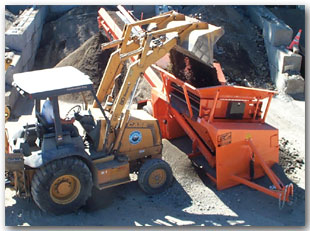 A crawler loader busy poring dirt into an EZ Screen Machine. 