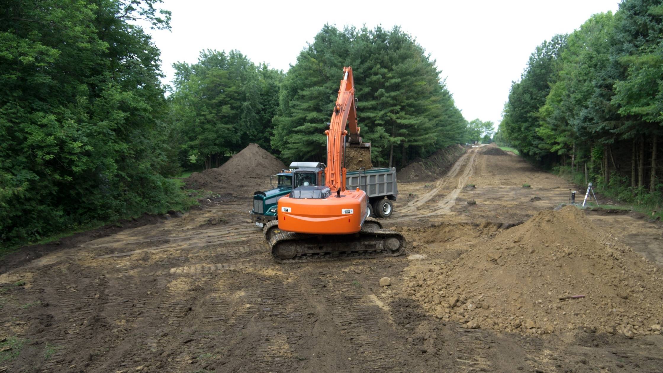 A crane dropping topsoil into the back of a truck