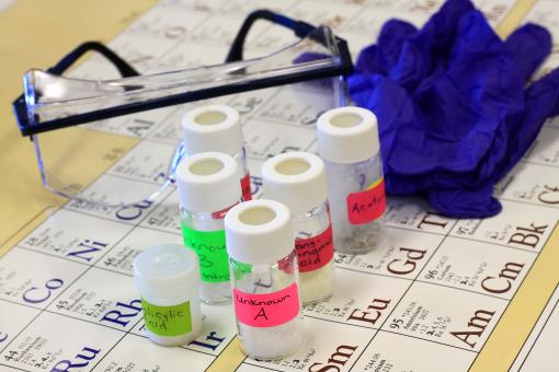 Various testing tubes alongside gloves and safety glasses. 