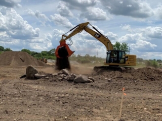 An excavator sifting soil with the SB16 attachment.