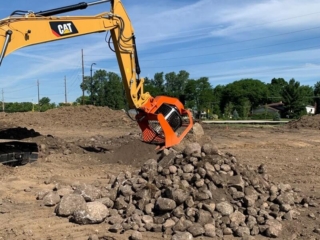 An excavator hovering the SB16 screening bucket above a pile of rocks.