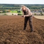A lady standing in a field of topsoil